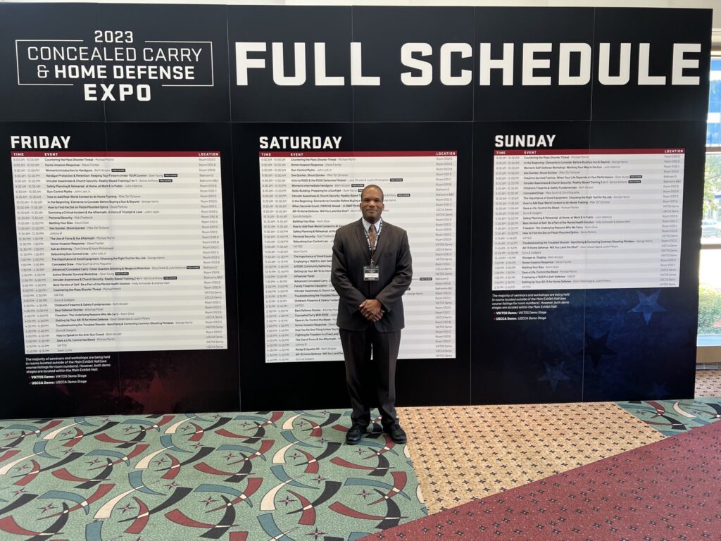 Attorney Eric Puryear standing in front of the schedule at the USCCA expo